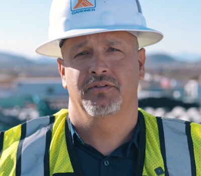 Employee-owner Jacob Gamboa wearing a white hard hat and high visibility vest.