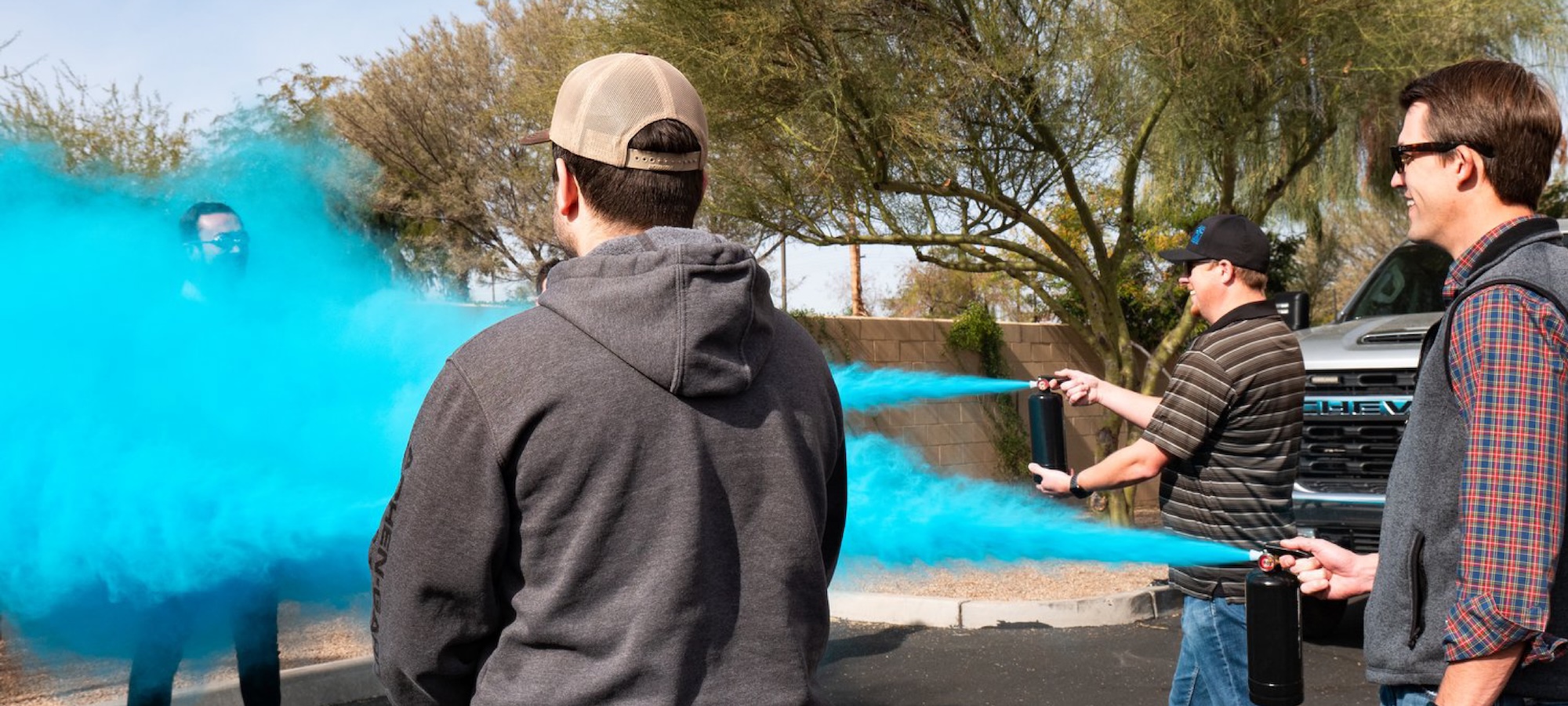 Three men spray a fourth man with blue colored chalk as part of a fundraiser.